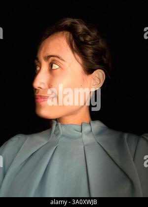 Ritratto di una donna con i capelli intrecciati, che indossa un abito casual su sfondo nero. Foto Stock