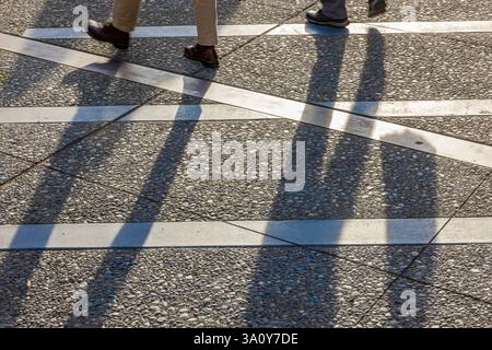 Ombre di persone che attraversano Alaska Way a Seattle, Washington State, Stati Uniti Foto Stock