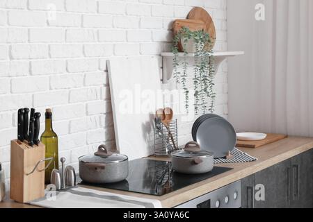 Ripiani in legno con portapiastre, tagliere, utensili e fornelli elettrici in una cucina moderna Foto Stock