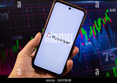 BOGOTÀ, COLOMBIA - 05 MARZO 2025 uno smartphone con logo payoneer e interfaccia pioneer sfocata sullo sfondo Foto Stock