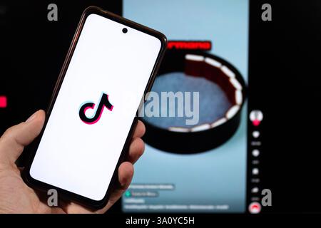 BOGOTÀ, COLOMBIA - 05 MARZO 2025 uno smartphone con logo tiktok e un'interfaccia social media sfocata sullo sfondo Foto Stock