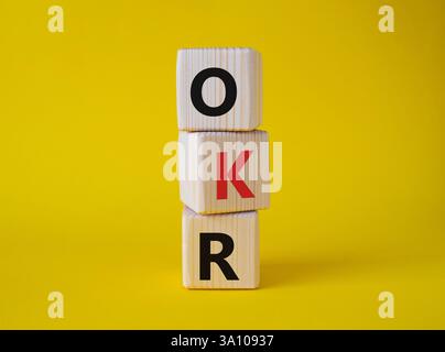 Obiettivi OKR e simbolo dei risultati chiave. Cubi in legno con parole obiettivi OKR e risultati chiave. Bellissimo sfondo giallo. Business e OKR. Foto Stock