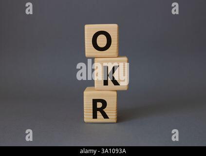 Obiettivi OKR e simbolo dei risultati chiave. Cubi in legno con parole obiettivi OKR e risultati chiave. Splendido sfondo grigio. Obiettivi aziendali e OKR Foto Stock