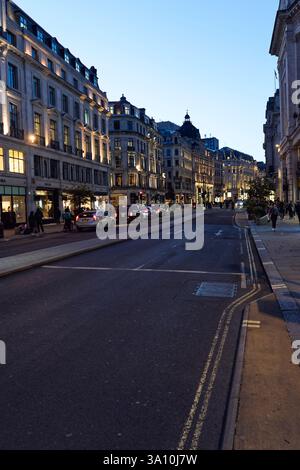 Architettura classica di Regent Street con negozi illuminati e lampioni al crepuscolo, West End, Londra, Inghilterra, Regno Unito. Foto Stock
