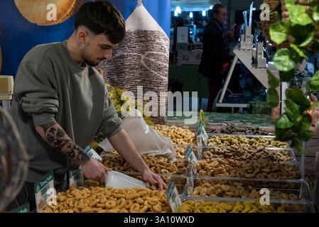 Venditore non identificato di prodotti alimentari tipici regionali alla fiera. Taralli dalla Puglia in primo piano. Foto Stock