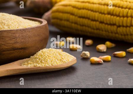Farina di mais in ciotola di legno e cucchiaio con semole di mais essiccate, noccioli su tavola rustica. Ingredienti di mais concetto Foto Stock