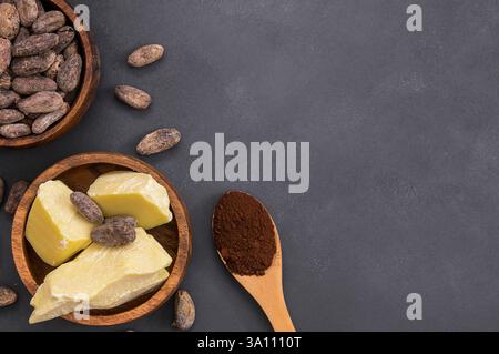 Burro di cacao o olio solido di cacao con cacao in polvere nel cucchiaio e fagioli di cacao crudi in ciotola di legno sullo sfondo rustico, olio naturale sano Foto Stock