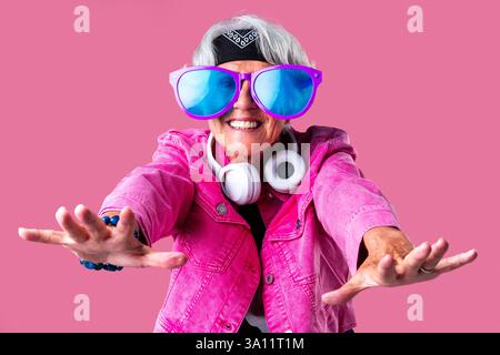 Bella donna anziana con capelli grigi che indossa un ritratto colorato ed elegante in studio - allegra vecchia nonna con uno stile alla moda Foto Stock
