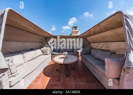 un'immagine ravvicinata di divani coperti all'aperto sulla soleggiata terrazza dell'attico sul tetto Foto Stock