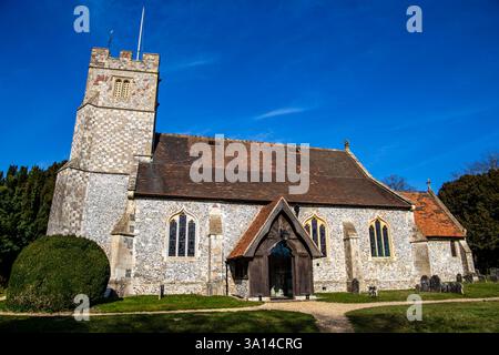 Storica chiesa in pietra con un alto campanile sotto un cielo azzurro, circondata da alberi e erba in un ambiente tranquillo, St Nicholas Church Longparish Foto Stock