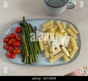 Pasta deliziosa con asparagi e pomodori ciliegini servita su un piatto Foto Stock
