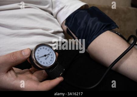 Controllo della pressione sanguigna con tonometro manuale, mani maschili da vicino Foto Stock