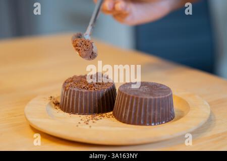 Colpo ritagliato di donna che prepara a mano una torta fatta in casa con una ricetta semplice, spolverando sopra zucchero a velo. Messa a fuoco selettiva. Foto Stock