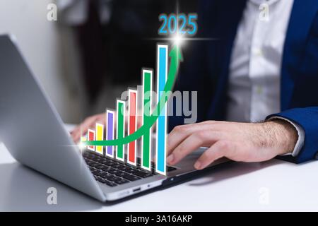 Uomo d'affari che utilizza un notebook con grafici e diagrammi con l'anno 2025 sullo schermo. Business e tecnologia Foto Stock