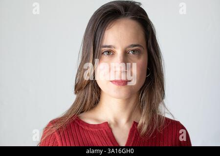 Ritratto in studio di una giovane donna sicura di sé che indossa una camicetta rossa, in posa su uno sfondo bianco Foto Stock