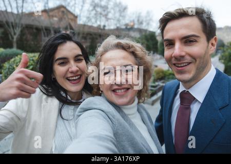 Team aziendale felice di scattare un selfie mostrando i pollici in alto all'aperto Foto Stock