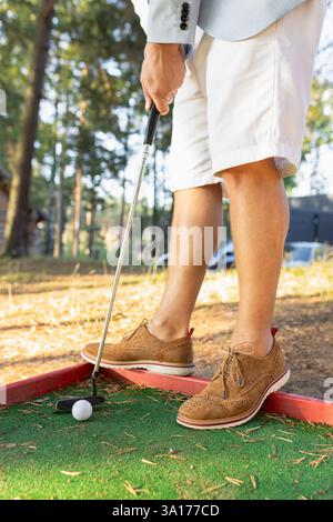 Uomo elegante in pantaloncini bianchi e scarpe scamosciate con mini golf club Foto Stock