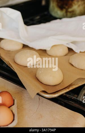 I panini di lievito naturale si ergono sul piano cottura ricoperti di telo da tè Foto Stock
