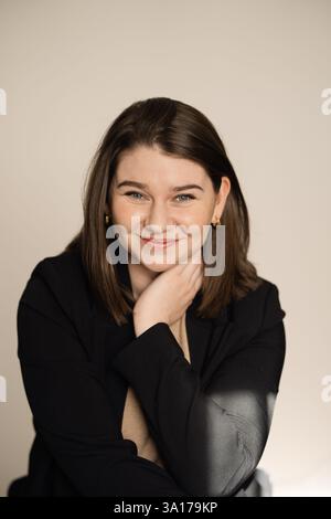 Donna sorridente in un blazer nero con luce soffusa sul viso Foto Stock