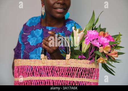 Donna che tiene in mano una borsa in tessuto rosa con fiori e sorridente Foto Stock