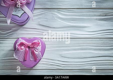 Piccole scatole in metallo a forma di cuore su tavola in legno per festeggiare Foto Stock