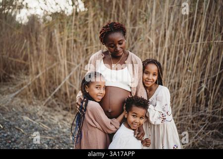 Madre incinta nera e bambini di corsa mista toccando la pancia Foto Stock