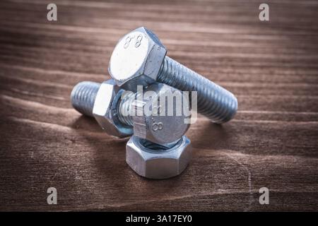 Coppia di bulloni filettati in metallo e dadi a vite sul concetto di riparazione di pannelli in legno vintage Foto Stock