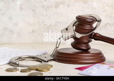 Carte di credito, martelletto del giudice e manette sul tavolo su sfondo grunge bianco. Concetto di debito Foto Stock