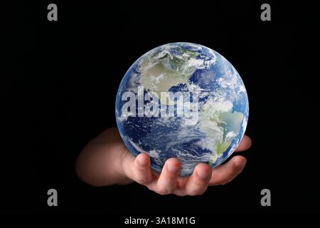 Pianeta nelle nostre mani. Uomo che tiene il modello della Terra su sfondo nero, primo piano Foto Stock