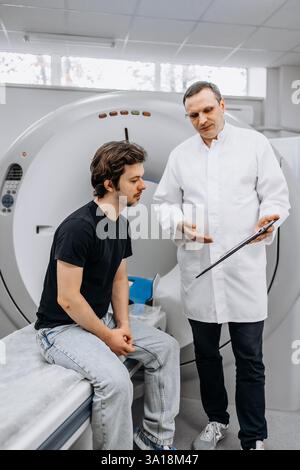 Un medico dedicato completa un esame RM mentre interagisce con un paziente. Questa immagine mostra professionalità e compassione nel settore sanitario Foto Stock