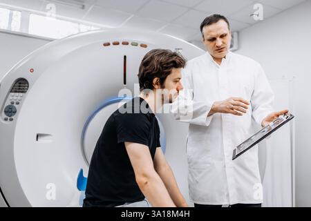 Un medico dedicato completa un esame RM mentre interagisce con un paziente. Questa immagine mostra professionalità e compassione nel settore sanitario Foto Stock