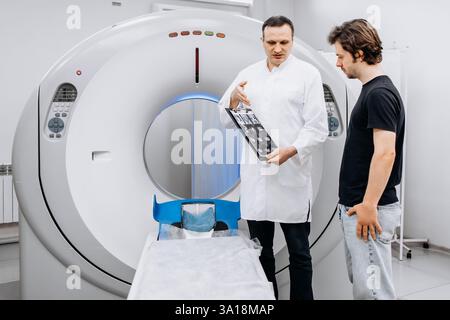 Un medico dedicato completa un esame RM mentre interagisce con un paziente. Questa immagine mostra professionalità e compassione nel settore sanitario Foto Stock