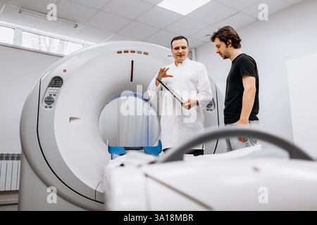 Un medico dedicato completa un esame RM mentre interagisce con un paziente. Questa immagine mostra professionalità e compassione nel settore sanitario Foto Stock