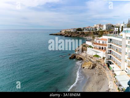 Vista pittoresca della costa di Nerja in Spagna, con una spiaggia affascinante, edifici bianchi e il tranquillo mare Mediterraneo su un cielo blu. Foto Stock