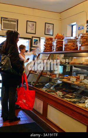 I clienti possono curiosare tra dessert, dolci e prelibatezze in una caffetteria e panetteria Foto Stock