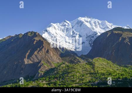 Il Rakaposhi Peak torreggia maestosamente sul villaggio di Minnapin, nel distretto di Nagar. Un rifugio tranquillo nascosto nella catena montuosa di Karakoram. Foto Stock