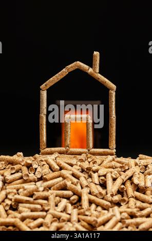 Casa in miniatura fatta con pellet di legno. Concetto di riscaldamento con camera di combustione in background. Foto Stock