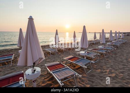 Chiuso ombrelloni e sedie in un bel tramonto. il cielo è rosso e arancione. Concetto di vacanza. Foto Stock