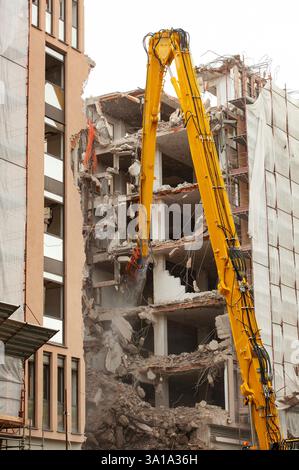 Demolizione di un edificio di nuova costruzione, utilizzando un escavatore speciale-cacciatorpediniere. Completare altamente meccanizzata di demolizione di strutture edili. Foto Stock