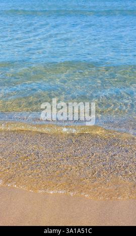 Ambiente tranquillo di acque cristalline che lambiscono dolcemente su una spiaggia di sabbia dorata, creando un'atmosfera serena e invitante Foto Stock