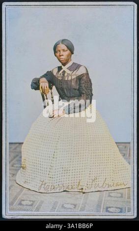 Harriet Tubman, attivista afroamericano contro la schiavitù (c1820-1913), è nato in schiavitù nel Maryland. Scappò nel 1849, divenne una leader abolizionista e fu attiva come "direttore" nella Ferrovia sotterranea, la rete che aiutò gli schiavi a fuggire per raggiungere la sicurezza. Si trova leggermente girata a destra e si spegne dalla fotocamera. La sua mano destra poggia sulla schiena di una sedia di legno e la sua mano sinistra poggia in grembo. Un tappeto modellato copre il pavimento e la parete o goccia dietro di lei è un colore chiaro vuoto. Tubman indossa un bodice nero che si bottoni al centro della parte anteriore e ha fatto cadere la slitta Foto Stock