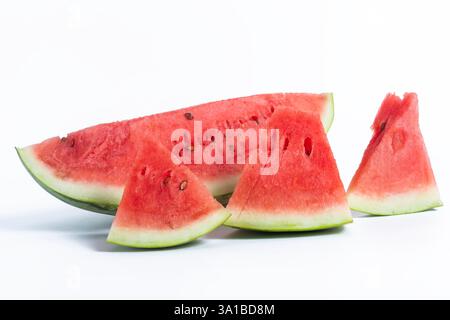 Un primo piano di fette di anguria vibranti e succose splendidamente disposte su uno sfondo bianco, a simboleggiare la freschezza e l'estate. Foto Stock