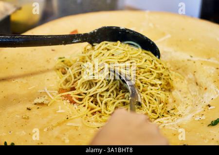 Augusta, Baviera, Germania - 7 marzo 2025: Gli spaghetti freschi vengono gettati in una grande pagnotta di parmigiano per assorbire l'intenso sapore di formaggio **** gli spaghetti Frische werden in einem großen Parmesanlaib geschwenkt, um den intensiven Käsegeschmack aufzunehmen Foto Stock