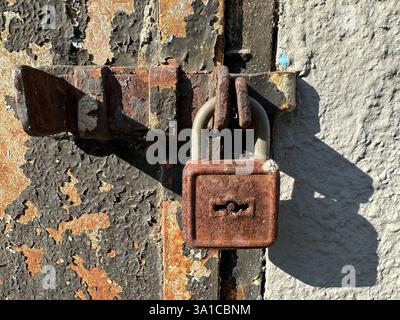Un vecchio lucchetto arrugginito in primo piano su un muro Foto Stock