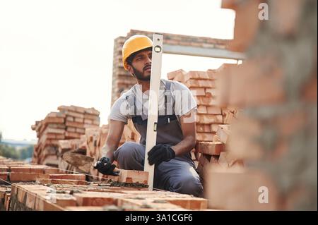 Utilizzando il livellatore. Bell'uomo indiano e' sul cantiere. Foto Stock