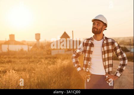 L'uomo con elmetto e' all'aperto contro la luce del tramonto. Scena rurale. Foto Stock