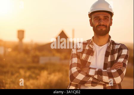 L'uomo con elmetto e' all'aperto contro la luce del tramonto. Scena rurale. Foto Stock