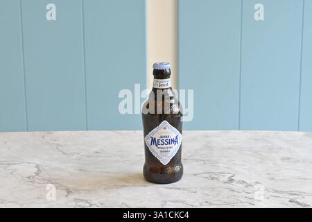 Una bottiglia di birra con un'etichetta blu con la scritta "MESSINA". La bottiglia è seduta su un tavolo Foto Stock