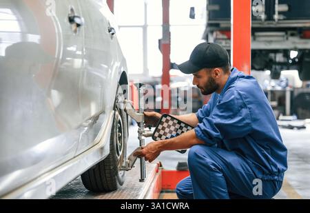 Attenzione al disco ruota. Meccanico che lavora in garage. Servizio di riparazione. Foto Stock