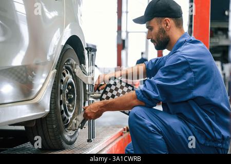 Attenzione al disco ruota. Meccanico che lavora in garage. Servizio di riparazione. Foto Stock